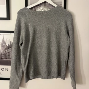 Grå stickad tröja med rund hals - Mysig grå stickad tröja med rund halsringning och långa ärmar. Tröjan har ribbade muddar vid ärmslut och nederkant, perfekt för kyliga dagar. Enkel och stilren design som passar till det mesta.