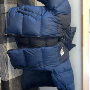 Blå och svart dunjacka The North Face XS - Säljer en blå och svart dunjacka från The North Face i storlek XS. Jackan har en klassisk pufferstil med dragkedja framtill, höga krage och två sidofickor med dragkedja. Perfekt för kalla dagar och riktigt snygg streetstil. Storlek xs skulle säga att den passar nästan upp till storlek M. Går att förhandla vid snabb affär❤️