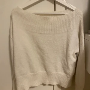 Offshoulder vit stickad tröja - Supermysig vit stickad tröja med bred ribbad kant upptill och nertill. Offshoulder-modell som ger en chill och trendig vibe. Perfekt att matcha med jeans eller kjol för en snygg look.