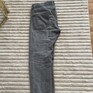 Grå jeansbyxor  - Snygga grå jeansbyxor med klassisk femficksmodell. Jeansen har en rak passform och är tillverkade i mjukt denimtyg. Perfekta för dig som gillar en stilren och enkel look. Midjan är normal och färgen är en tvättad grå nyans.