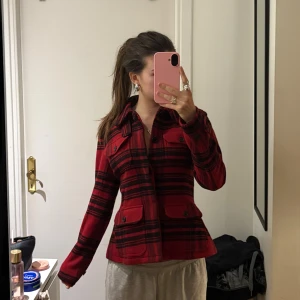 Rutig röd jacka från Polo Ralph Lauren - Säljer en snygg röd och svart rutig jacka från Polo Ralph Lauren. Jackan har markerad midja, klassisk krage, knappar framtill och fickor med lock. Aldrig använt pga felköp! 💕 Nypris ca 6000kr