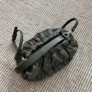 Grön omlott axelväska med dragkedja - Snygg grön axelväska med omlott-design och rynkade detaljer. Väskan är från nakd 