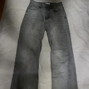 Grå jeans från Perfect Jeans, storlek 34 - Säljer ett par grå jeans från Perfect Jeans i storlek 34. Jeansen har klassisk femficksdesign, raka ben och råa kanter nertill för en avslappnad vibe. Materialet är denim och färgen är tvättad grå, vilket ger en cool och tidlös look.