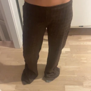 Nelly byxor - Säljer ett par bruna byxor med vid passform och snyggt strukturerat tyg. Byxorna har låg midja och raka ben som faller snyggt. Perfekta för dig som gillar en chill och trendig look. Färg och material ger en cool vibe till outfiten. Har klippt av dom då dom var för långa annars helt nya💕