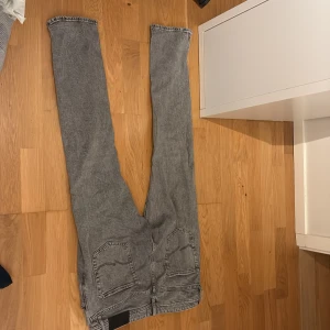 Gråa Jack n Jones jeans - Säljer ett par grå jeans från Jack & Jones, modell Tapered Mike.  Storlek 30/32. Säljes då jag helt enkelt inte använder dem längre då jag har många andra par jeans. Bra skick, köptes för ca 1 år sedan för 599 säljes nu för 299kr.