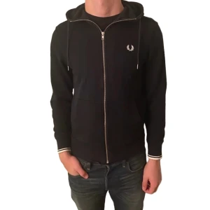 Fred Perry mörkblå hoodie S - Mörkblå hoodie från Fred Perry med dragkedja i storlek S med riktigt nice passform! Klassisk Fred Perry-logga broderad på bröstet, vilket ger en lyxig men stilren känsla. Längd: 62cm Bröstvidd: 48cm                Nypris: 2000kr. Mitt pris: 550kr                                            Pris kan diskuteras!