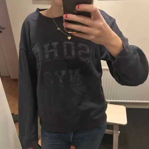 Grå sweatshirt från hm - Mörkblå sweatshirt från H&M med trycket SOHO NYC framtill. Tröjan har en avslappnad passform, rund halsringning och långa ärmar med breda muddar. Perfekt för en chill och stilren look.