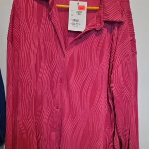 Rosa skjorta från Flam Mode M/L - Säljer en rosa skjorta från Flam Mode i storlek M/L. Skjortan har ett vågigt strukturmönster, klassisk krage och knäppning framtill. Långärmad och i ett mjukt, lätt material som känns skönt mot huden. Perfekt för dig som gillar färg och unika detaljer.