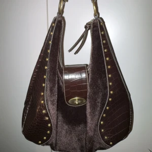 Vintage hobo bag - Vintage väska i hobo modell från märket David Jones🫶🏻  🖤 Framsida av päls, guldnitar som detaljer 🖤 Stängs med dragkedja och guldknäppet 🖤 Stor och rymlig i storleken, sitter bekvämt på axeln 🖤Superfint skick, endast en fläck i botten på tyget, se bild. 🖤 Har två små fickor på insidan, en har dragkedja, se bild. 🖤Ej äkta päls/skinn!