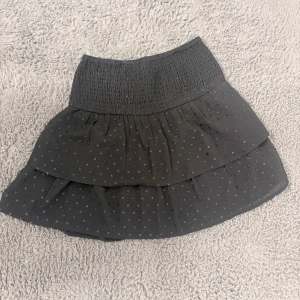 Svart volangkjol från Gina Tricot - Supersöt svart kortkjol från Gina Tricot med små prickar och volanger. Väldigt bra skick, andvänt få gånger 