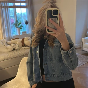 Ljusblå croppad jeansjacka - Säljer en snygg ljusblå jeansjacka med klassisk design och croppad passform. Jackan har silverfärgade knappar framtill och vid ärmsluten, samt två bröstfickor. Perfekt för dig som vill ha en stilren och trendig look. (Aldrig använd) Storlek 158-164 passar xs💗 hör av er vid frågor💗