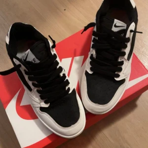 Travis Scott x Nike Dunk Low i svart och vitt - Säljer ett par Travis Scott x Nike Dunk Low i svart och vitt. Skorna har den klassiska låga siluetten med svart tå och snörning, kombinerat med vita läderpaneler och en clean vit sula. Ett par eftertraktade “Cactus Jack”-sneakers som tar streetstyle till nästa nivå. ✔️ Helt nya – aldrig använda ✔️ Originalkartong medföljer ✔️ Pris går att diskutera 💸 Perfekta för dig som vill sticka ut eller lägga till en exklusiv sneaker i samlingen