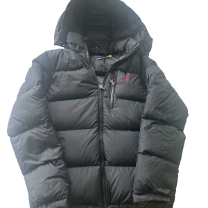 Svart puffer Polo Ralph Lauren - Svart pufferjacka från Polo Ralph. moddelen är en Gorham down jacket. Den är i väldigt bra skick inga skador.  QR coden i jackar går att skanna och leder dig till autenticitet. säljer pga av att den inte används.