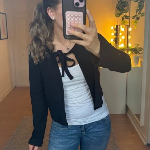 Svart stickad kofta - Svart stickad kofta från 157 i storlek XS. Modellen är croppad och har långa ärmar samt en snygg knytning framtill. Inga defekter och knappt använd. 