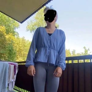 Blå v-ringad skjorta med knappar - Säljer en blå skjorta med v-ringning och knappar framtill. Skjortan har lång ärm, lätt volang nedtill och ett löst, avslappnat fit. Materialet känns som tunn bomull och har en diskret struktur. Perfekt för dig som gillar chill och enkel stil. Från vero Moda 