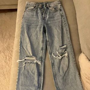 Jeans H&M - Jeans från HM med hög midja och raka ben. Jeansen har slitna detaljer och hål vid knäna. 