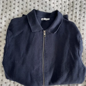 Mörkblå kofta med dragkedja från Zara - Snygg mörkblå kofta från Zara med hel dragkedja framtill och klassisk krage. Tröjan är stickad och har långa ärmar, perfekt för lager-på-lager. Enkel och stilren design som funkar till många outfits. Nästan aldrig använd 