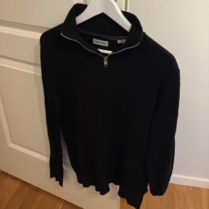 Svart half zip tröja Jack & Jones - Svart långärmad tröja från Jack & Jones med half zip-dragkedja i halsen. Riktigt snygg tröja som funkar till typ allt. Den är som sagt från Jack n Jones och köptes för ca 400-500kr och säljes nu för 149kr. Den är i bra skick 