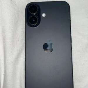 iPhone 16 - Snygg iPhone 16 i svart med dubbla kameror och elegant design. Baksidan ser ut att vara i mycket gott skick utan synliga repor eller skador. Perfekt för dig som vill ha en modern och kraftfull smartphone med hög bildkvalitet. 100% batterihälsa, tillkommer inte med box och kvitto