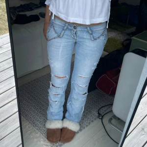 Blåa lågmidjade jeans med slitningar - Assnygga ljusblåa jeans med hål säljer då jag behöver pengar de är i toppen skick!
