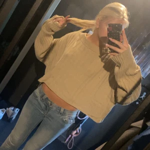 Beige croppad stickad tröja - Säljer en beige croppad stickad tröja med breda ärmar och ribbad struktur. Tröjan har en loose passform och är perfekt för lager-på-lager. Enkel och stilren design som passar till jeans eller kjol.
