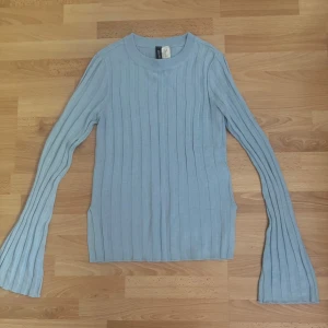 Ljusblå ribbad stickad tröja Divided - Supersöt ljusblå stickad tröja från Divided i storlek XS. Tröjan har ribbat mönster, långa ärmar med lätt utsvängda avslut och rund halsringning. Perfekt för dig som gillar en enkel men trendig look.