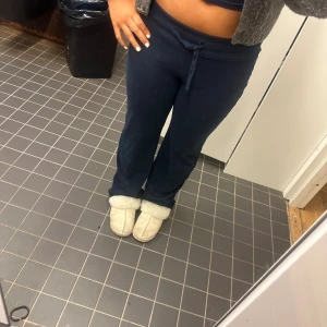 Mörkblå mjukisbyxor från Gina Tricot - Mörkblå mjukisbyxor från Gina Tricot i storlek S. Byxorna har dragsko i midjan och raka ben med lite vidare passform. Tillverkade i mjukt bomullsmaterial, perfekta för chill dagar. Klassisk look med ribbad midja och bekväm känsla.