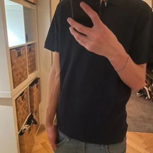 Marinblå Helly Hansen piké - Säljer en marinblå piké tröja från Helly Hansen med klassisk krage och HH-logga på ärmen. Pikén är kortärmad och har en clean, stilren look som passar perfekt till jeans. Materialet känns mjukt och bekvämt mot huden.