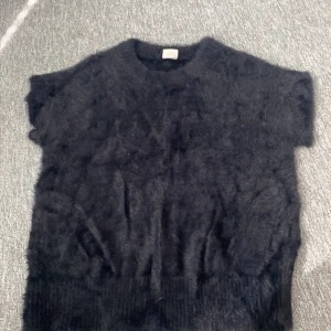 Svart fluffig stickad tröja Stories - Mysig svart stickad tröja från & Other Stories i storlek S. Tröjan är kortärmad och har en fluffig, mjuk. Inte kommit till användning 