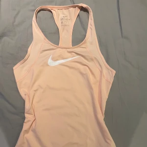 Nike linne - Säljer en ljusrosa linnetopp från Nike i storlek S. Toppen är tillverkad i Dri-Fit polyester som andas bra 😍. Knappt använd