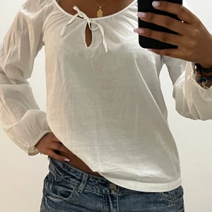 Vit blus med knyt från Filippa K - Säljer en luftig vit blus från Filippa K i storlek M. Blusen har långa ärmar med en söt knytning framtill.