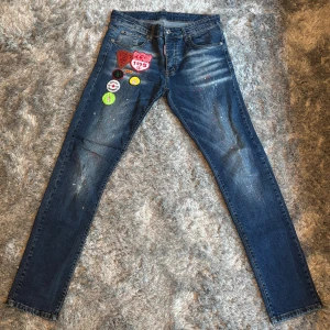 Blå skinny jeans från Dsquared2 - Snygga blå jeans från Dsquared2 med skinny passform. Jeansen har coola broderade patches och färgstänk framtill som ger en unik vibe. Klassisk femficksmodell med läderpatch bak i midjan. 