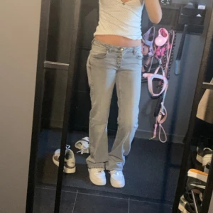 Ljusblå raka jeans med låg midja - Säljer ett par ljusblå jeans med låg midja och raka ben. Jeansen har klassisk femficksdesign och stängs med knapp och dragkedja. Perfekta för en chill och avslappnad stil. Passar dig som gillar en enkel och clean look.