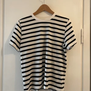 Randig svartvit t-shirt i bomull - Snygg t-shirt med klassiska svarta och vita ränder. Modellen har rund halsringning och korta ärmar. Tillverkad i mjuk bomull som är skön mot huden! 