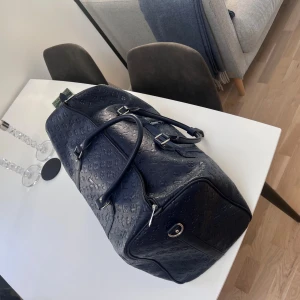 Mörkblå  Sweet Years väska  - Stor och rymlig mörkblå resväska från Sweet Years med präglat mönster över hela väskan. Väskan har två rejäla handtag, silverfärgade detaljer och dragkedja. 