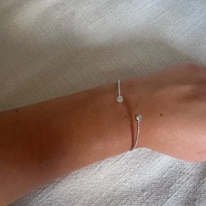 Caroline svedbom  - Snyggt och stilrent armband i silverfärg med två glittrande kristaller i ändarna, från Caroline Svedbom. Armbandet har en tunn och elegant design som ger en modern vibe. Perfekt för dig som gillar diskreta men ändå lyx. I fint skick 🌸