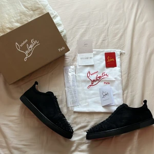 Christian Louboutin svarta sneakers med nitar - Svarta sneakers från Christian Louboutin i mocka med coola svarta nitar på tån och klassisk röd sula. Skorna har snörning och en stilren, rund tå. Kommer med originalkartong, dustbag och äkthetsbevis. Perfekta för dig som vill sticka ut med lyxig streetstyle. Har fyllt i priset på kvittot för att tydligare kunna se original priset, original texten på kvittot står också på kvittot men väldigt svagt då det är slitage på kvittot! 2hands ägare, nyköpta https://eu.christianlouboutin.com/se_en/storelo