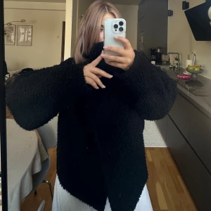 Svart teddyjacka med oversized passform - Mysig svart teddyjacka med oversized siluett och bred krage. Jackan har lång ärm och stängs med knappar framtill. Materialet är fluffigt. Välanvänd men i bra skick 