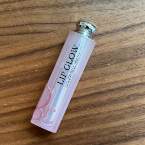 Dior Addict Lip Glow 031 Strawberry - Dior Addict Lip Glow Color Reviver Balm i nyansen 031 Strawberry. Lyxigt läppbalsam med rosa transparent hylsa och silvrig detalj. Ger en fräsch rödrosa ton och återfuktar läpparna med en lätt glansig finish. Perfekt för dig som vill ha både färg och vård.