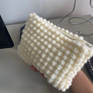 Virkad necessär med dragkedja - Superfin handgjord neccesär i virkat material med bubblig struktur. Necessären är smörfärgad  och har en dragkedja upptill samt vitt innerfoder. Perfekt för att förvara småsaker eller smink. Går även att använda som handväska. Egenvirkad!!💕