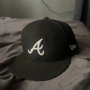 Svart New Era 59FIFTY Atlanta keps - Svart New Era 59FIFTY keps med Atlanta Braves A-logga framtill i vitt. 