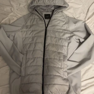 Ljusgrå pufferjacka från Primark - Snygg ljusgrå pufferjacka från Primark i storlek small. Jackan har huva, hel dragkedja och quiltad framsida och rygg. Tillverkad i syntetmaterial och perfekt för kyliga dagar. Enkel och clean design som passar till det mesta.