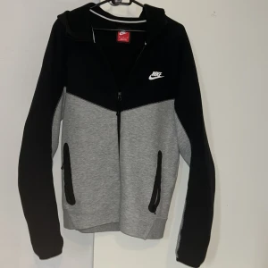 Nike Teech Fleece Svart och Grå - Nike Tech Fleece i svart och grått. Skön passform och perfekt för chill eller träning. Tillverkad i mjukt material som känns bekvämt hela dagen. Passar personer med 180-185 i längd