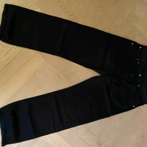 Levi's 551 svarta jeans W34 L36 - Svarta Levi's 551 jeans med klassisk femficksdesign och raka ben. Jeansen har en snygg, enkel look och är tillverkade i slitstarkt denim. Perfekta för dig som gillar en tidlös och clean stil. OBS! Jeansen är nästan 8cm korta på mig som är 186