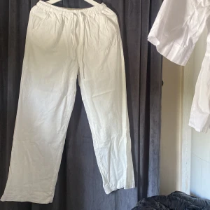 Vita linnebyxor med resårmidja M - Säljer ett par vita linnebyxor i storlek M. Byxorna har resår i midjan och dragsko för extra komfort, samt sidfickor. De är raka i modellen och perfekta för en chill och luftig stil.