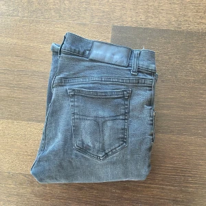 Tiger Of Sweden Jeans - Slim fit jeans i svart tvätt med klassisk femficksdesign och smala ben. Snyggt slitna detaljer och bekväm passform. Perfekta för dig som gillar en stilren look med lite edge.