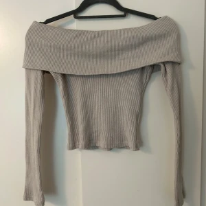 Beige offshoulder topp Gina Tricot - Superfin ribbad offshoulder topp från Gina Tricot i beige i storlek XS. Säljes för 150kr