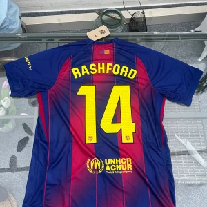 🔥 Rashford #14 Barcelona 25/26 Hemmatröja L 🔥 - Ny Barcelona hemma-tröja 2025/2026 med Rashford #14 ⚽💥 	•	Storlek: L 	•	Skick: Ny, aldrig använd, etiketter kvar ✨ 	•	Färg: Klassisk röd/blå 🔴🔵 	•	Material: Mjuk, lätt & andas bra 🌬️ 	•	Tryck: Officiellt namn + nummer på ryggen, klubbmärke på bröstet  Perfekt för matchdag, samlaren eller vardagsstyle 😎 Kan skickas 📦 eller hämtas lokalt 🏠 