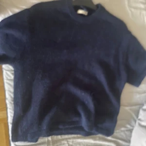 Mörkblå stickad tröja Gina Tricot M - Mysig mörkblå stickad tröja från Gina Tricot i storlek M. Tröjan har en klassisk rund halsringning och korta ärmar, perfekt för lager-på-lager. Den stickade strukturen ger en chill och avslappnad vibe.