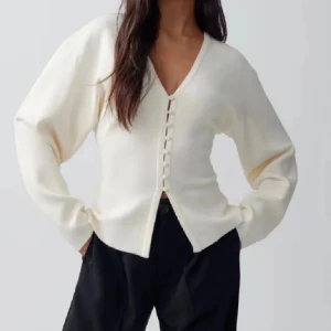  kofta  - Säljer en stilren vit kofta med v-ringning och snygga knappar framtill. Tröjan är ribbad och har långärmad passform med lite loose fit. Perfekt att slänga på sig över ett linne eller t-shirt för en chill look.